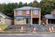 Housing developer levy funds fail to reach local communities due to systemic problems Wide shot front elevation of a vacant property at a housing development site in Northumberland, North East England. The two storey detached house is in the process of being built, there is a gravel area in front of it and orange cones placed around the perimeter of the plot. Behind the house is an area of trees, representing the housing developer contribution levy