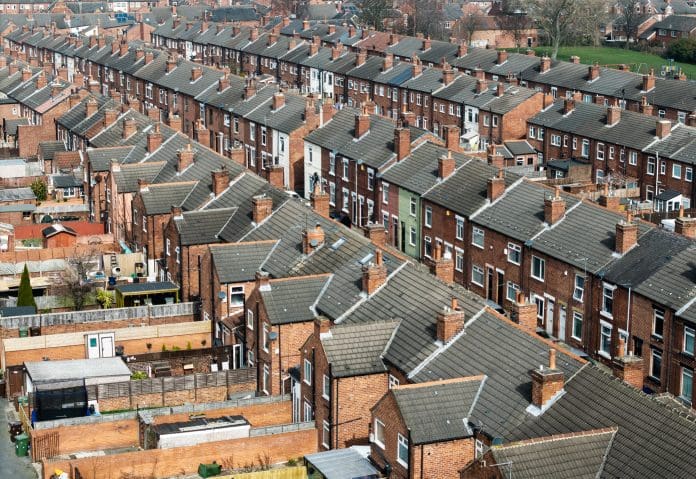 An aerial view above the rooftops of run down back to back terraced houses on a large residential estate in the North of England, representing the procurement act