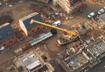 Last-minute Planning and Infrastructure Bill amendments send shockwaves through industry Aerial view of yellow mobile crane at construction site performing lifting operation, representing planning and infrastructure bill amendments