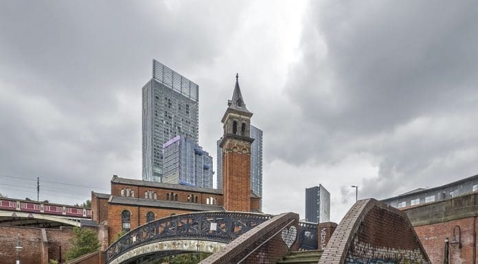 View across the canal at Castlefield in the centre of Manchester, UK. Reflections of a foot bridge and graffiti can be seen. There are no people in the photograph