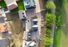 Current delivery projections to only meet 1.5 million new homes target by half Drone top down view of in a row, nearly completed detached and first time buyer homes seen on a typical British housing development site. Seen adjacent to farm fields, across the country lane, representing the 1.5m housing target