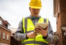 New AI regulation blueprint to speed up planning approvals Young caucasian male custruction worker on a building site looking at a digital tablet. Low angle, horizontal shot with copy space, representing a new ai regulation blueprint