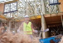 Labour shortages deepen as immigration policies tighten Male worker throwing sand with shovel against incomplete building. Confident engineer is working at construction site. He is in reflective clothing.
