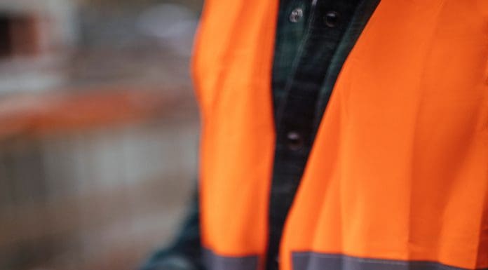 Unrecognizable construction worker using a digital tablet while working at a building site, representing Project Information Management