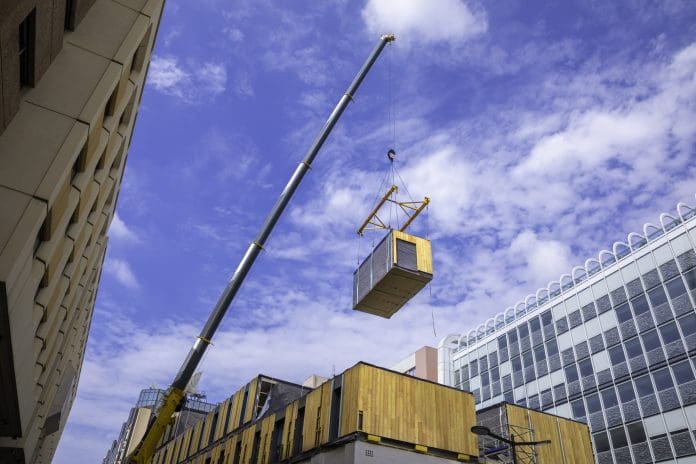Ireland’s offsite manufacturing sector: “We have capacity. What our members need now is a robust and reliable pipeline.” Modular wood commercial building prefabricated assembled with crane, representing Ireland's offsite manufacturing