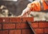 Building quality homes in large quantities Bricklayer laying another brick in the wall on construction site for sturdy wall