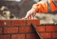 Building quality homes in large quantities Bricklayer laying another brick in the wall on construction site for sturdy wall