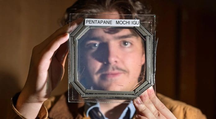 Abram Fluckiger holds up a sample panel square that has five sandwiched layers of a new material nearly transparent insulation material called MOCHI, which was designed buy CU Boulder researchers in physics professor Ivan Smalyukh’s lab. Credit: Glenn J. Asakawa/CU Boulder
