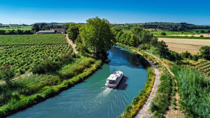 Aerial drone view of houseboat in Canal du Midi from above, family travel by boat, vacation in Southern France Aerial drone view of houseboat in Canal du Midi from above, family travel by boat, vacation in Southern France