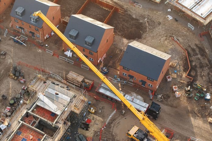 New Single Construction Regulator Prospectus published Aerial view of yellow mobile crane lifting materials on construction site, representing the new Single Construction Regulator prospectus