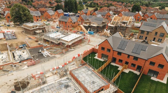 Construction workers are busy building new homes in a suburban neighborhood. Various houses are taking shape, while others are in different stages of completion.