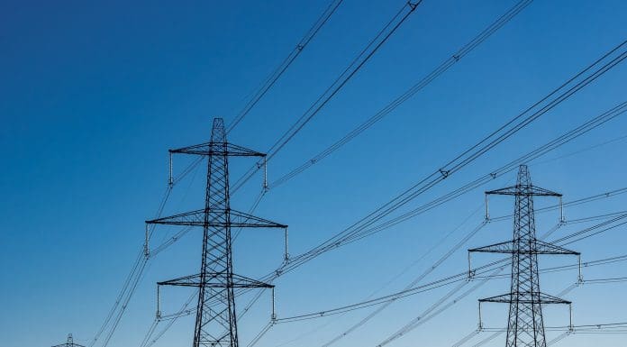 Electricity Pylons and field of cows with blue sky, representing united infrastructure acquisition