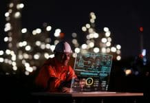AEC Technology Outlook 2026: Where is UK construction heading? Young engineer wearing an orange safety jacket and hard hat, working on a clear screen, creating and innovating with graphic input data. Representing the AEC Technology Outlook 2026