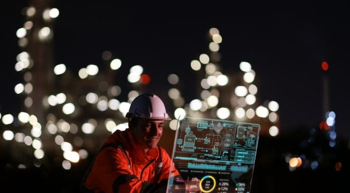 Young engineer wearing an orange safety jacket and hard hat, working on a clear screen, creating and innovating with graphic input data. Representing the AEC Technology Outlook 2026