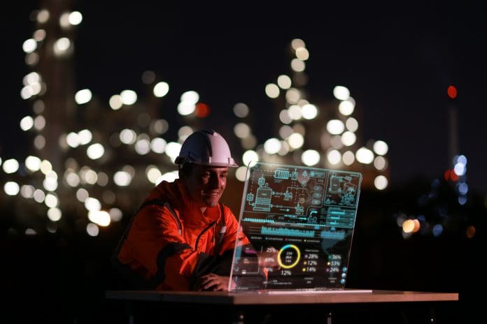 Young engineer wearing an orange safety jacket and hard hat, working on a clear screen, creating and innovating with graphic input data. Representing the AEC Technology Outlook 2026