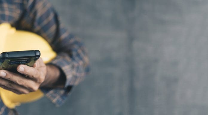 construction worker hands using smartphone on cement wall background with copy space