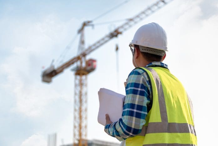 Tower crane drivers plan strike at end of month Engineering Consulting people on construction site holding blueprint in his hand and control workflow of the new building, representing the potential tower crane drivers strike