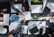 University of Cambridge joins CCBP Academic Advisory Group Top Down View of Diverse Team of Business Professionals and Engineers Working Together on Architectural Plans in a Corporate Office. Focused Colleagues Using Laptop, Tablet, Blueprints and Documents.