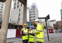Professional practical experience consultation launched by ARB A wide shot of three construction employees standing together outside a construction site. They are discussing plans together using blueprints and an electronic tablet. The two men and woman are wearing high-visibility clothing and hard hats, representing a new personal professional experience consultation