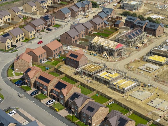 Industry welcomes Warm Homes Plan promise of £15bn for sustainable solutions Aerial view of new build housing with built in solar panels in the roof, England, representing changes proposed in the warm homes plan
