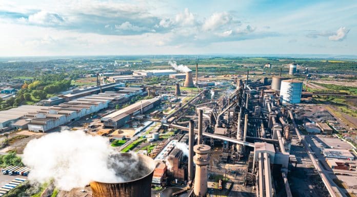Drone capturing a steel mill emitting smoke and steam during a vibrant sunset in Scunthorpe, uk