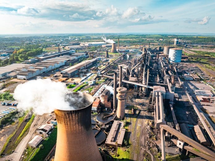Drone capturing a steel mill emitting smoke and steam during a vibrant sunset in Scunthorpe, uk