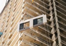 Social housing could be key to offsite manufacturing rebound Installing a piece of a modular facade on a building under construction, representing the role offsite manufacturing could play in social housing