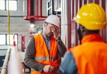 Number of UK construction companies in ‘critical’ distress rises by almost 50% Adult engineer feeling overwhelmed and having a headache, covering his face with his hand while standing in a factory during a difficult work situation, representing construction critical distress