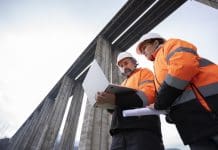 Designing for real-world structural behaviour with SCIA Engineer 2026 Team of experienced road engineers in safety gear and helmets discuss new viaduct blueprint of highway construction project. Building smart infrastructures. Representing SCIA Engineer 2026