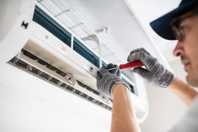 Technician with screwdriver repairing air conditioner at home The UK climate has changed to the point that drastic action is required, before things get worse, say the CCC