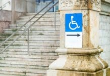 Communication is the key in a building full of accessibility barriers Addressing accessibility barriers in a Grade II listed building. Wheelchair accessibility sign mounted on a stone wall near outdoor stairs, representing inclusive design, accessibility, mobility rights, public infrastructure, and urban accessibility.