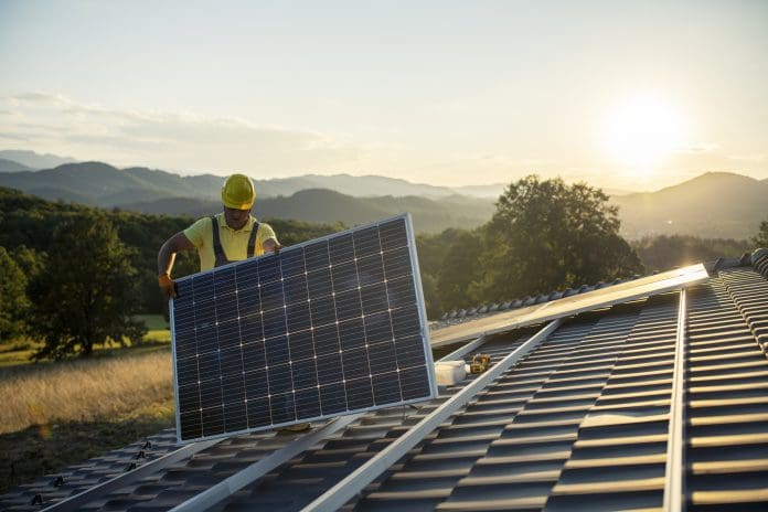 Technician fitting solar panels to a house roof. The RICS global sustainability guide illustrates how all professional surveyors can improve their sustainbility work
