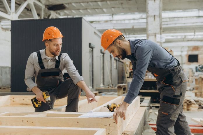 Construction workers building wooden frame in factory Angela Carney discusses how the industry should tackle the construction skills challenge
