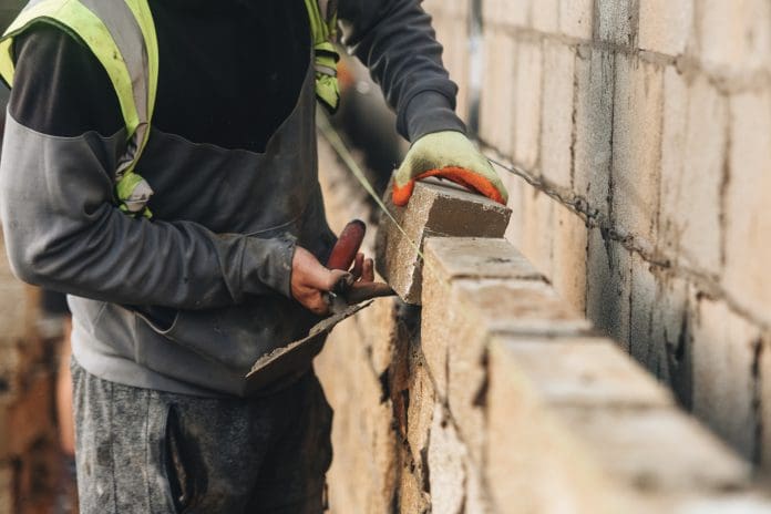 Bricklayer constructing stone wall using stone blocks, cement mortar mix and trowel The NFB has conducted research tracking unspent developer contributions