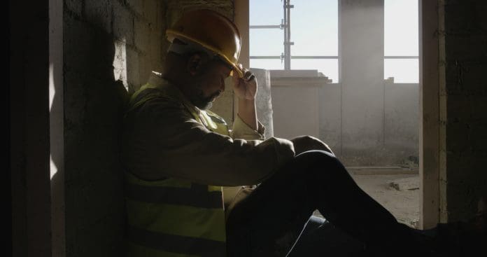 Construction site, thinking or man with safety, sad or overwhelmed with maintenance. Break, person or inspection with urban development, delay or engineer with fatigue or pressure to finish project The CLC have published a Mental Health code of practice to help employers ensure preventative support for their workers