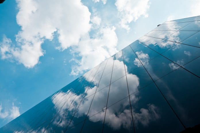 London Corporate Buildings Looking up at the glass facade on a building in the city of London with a blue sky and clouds above