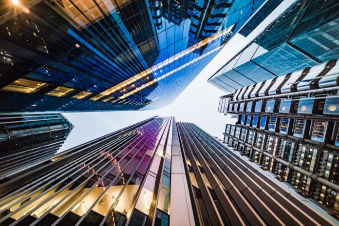 Extreme wide angle view directly up in the skyline of the financial district in down town central city of London, United Kingdom - creative stock image Highly detailed abstract and extreme wide angle view up towards the sky in the financial district on down town London City and its ultra modern contemporary buildings with iconic and unique architecture. Shot on Canon EOS R5 full frame with prime 10mm wide angle lens and toned in blue to give extra business feel overall. Image is ideal for background including plenty of copy space, suitable for various concepts of life - creative stock photo.
