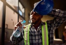Construction sites are not ready for extreme heat African American construction worker refreshing himself with a water at work.