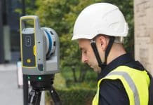 Geospatial surveys: The overlooked decision that shapes design certainty in construction A male worker in hi viz and white hard hat standing next to a laser scanner