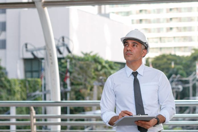 construction engineer standing holding agreement documents papers inspecting project development at the construction site Avon Combined Electrical Services files administration notice