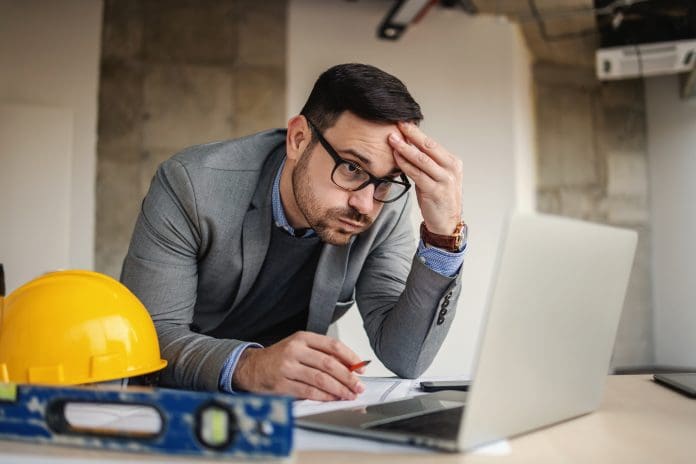 Focused architect holding his head, sights and looking at laptop. Something got wrong. The ONS construction stats for June 2026 show slow movement