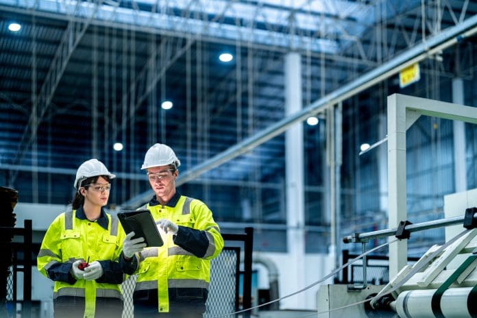 Male and female engineers in neat work clothes prepare and control the production system of large modern machines in a factory producing industrial technology products. europe's infrastructure will need connected data