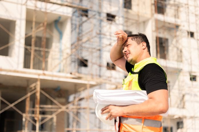 Tired Sweating Construction Worker On Building Site Under Sunlight Outdoor tradespeople urged to take precautions as another UK heatwave approaches