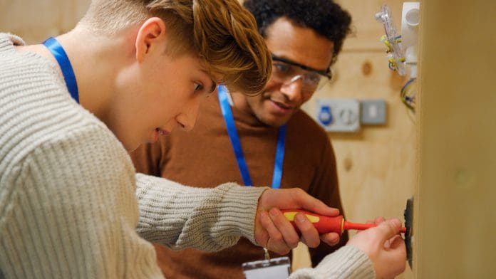 Male Tutor With Trainee Electricians In Workshop Studying For Apprenticeship At College Technical education could be the key to construction’s skills shortage