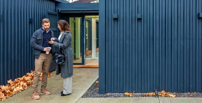 Couple discussing modular home made with shipping containers real estate options using smartphone How much extra does Passivhaus cost to build?