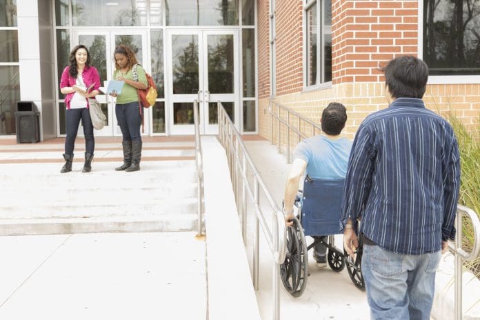 Education: Disabled student helped up wheelchair ramp. College campus. Mindset can be the biggest barrier to accessibility