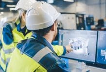 The digital journey for the built environment begins with data, not software Two workers in hard hats and high visibility jackets looking at a computer monitor displaying a digital model of a building project