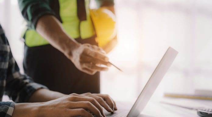 business man hand working and laptop with on on architectural project at construction site at desk in office.