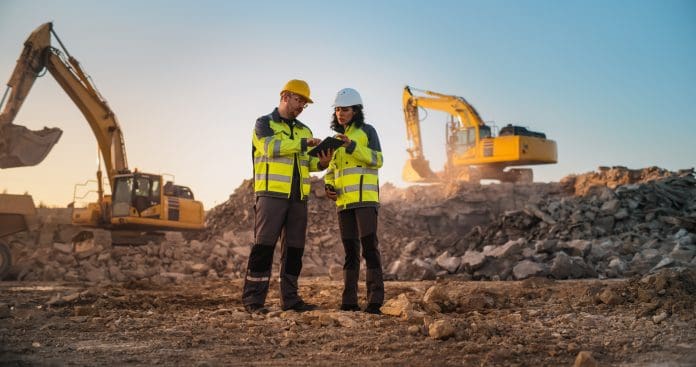 Caucasian Male Civil Engineer Talking To Hispanic Female Inspector And Using Tablet On Construction Site of New Apartment Complex. Real Estate Developers Discussing Business, Excavators Working. Geoworks discusses data-driven design