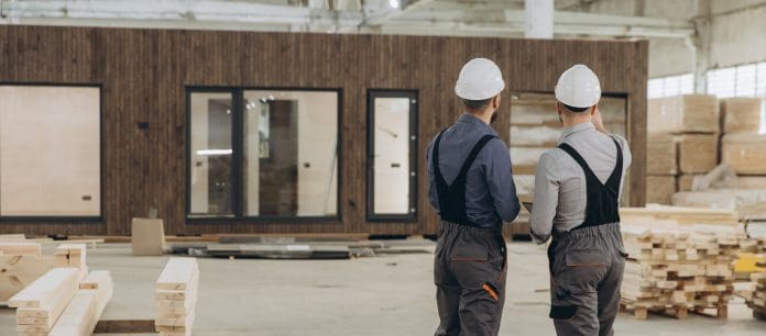 Engineers inspecting completed modular building in factory Two engineers are evaluating a finished prefabricated modular building inside a large factory, ensuring quality and compliance